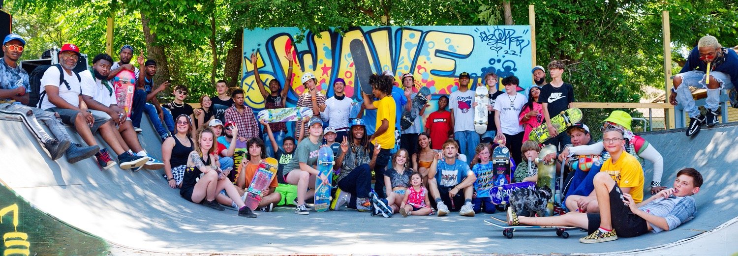 Some of the participants gather in front of the mural painted by Luis Valle, in town to work on the Wood County Unity Mural. It reads, "Wave, we're friendly." [see more skating]
